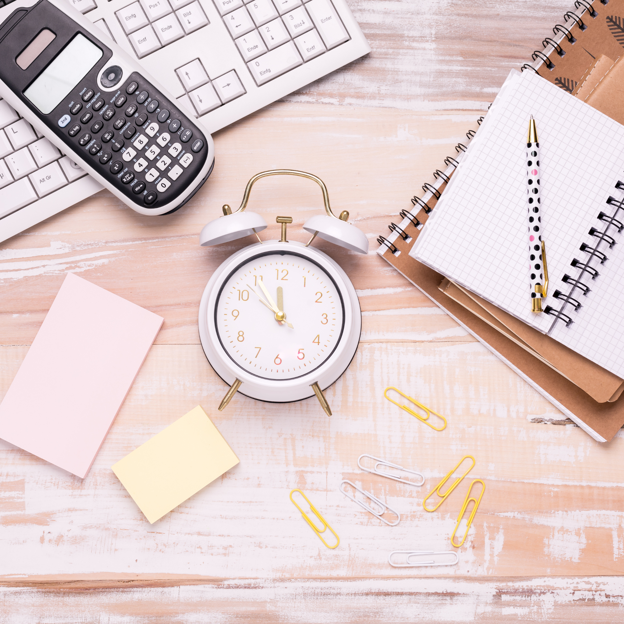 Schreibtisch mit einem Notizbuch, einer Uhr, einem Computer und Schreibmaterial