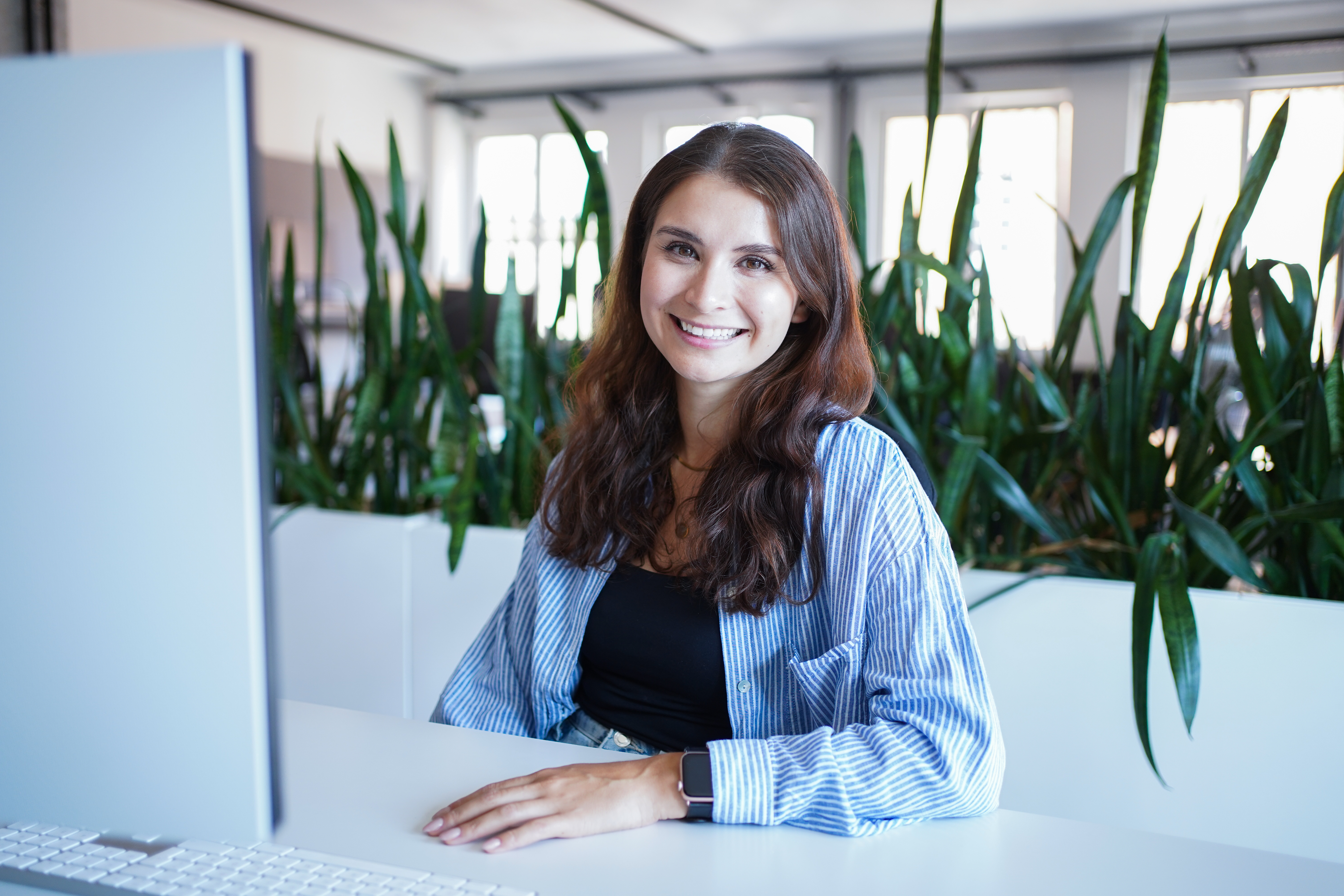 Julia Stadniczuk virtuelle Assistentin im Office vor dem Rechner am Schreibtisch lächelt in die Kamera