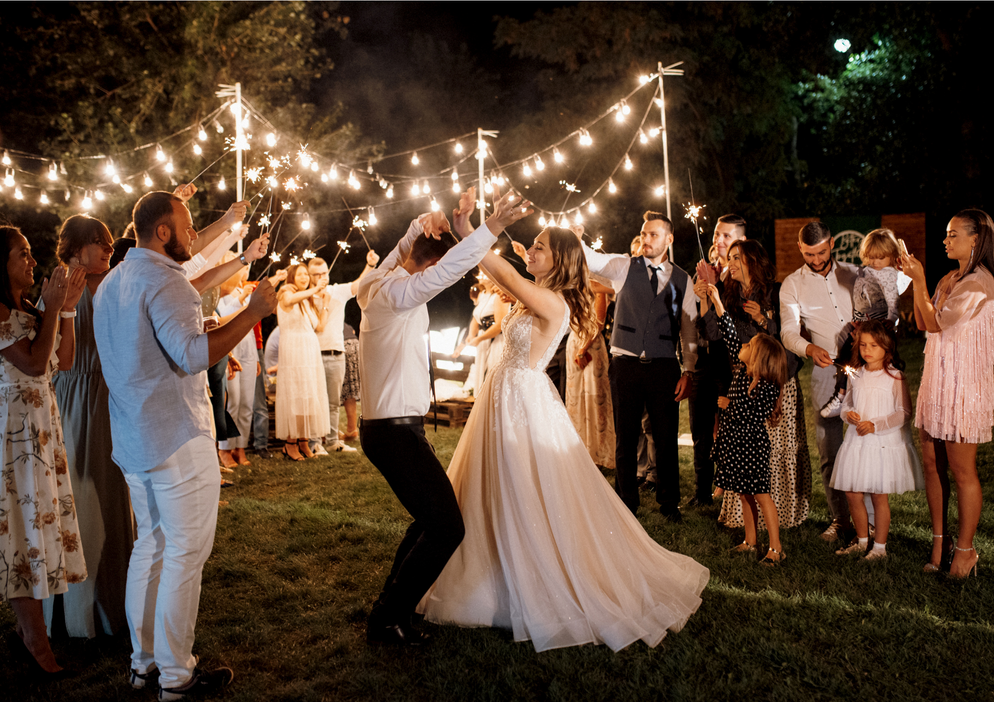 Hochzeitstanz des Brautpaares umgeben von den Gästen im Schein der Wunderkerzen und Lichterketten 