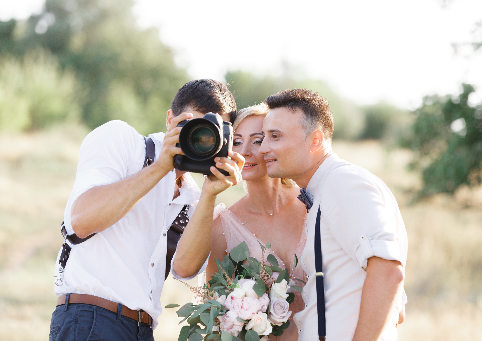 Hochzeitsfotograf zeigt dem Brautpaar die eben aufgenommenen Hochzeitsbilder