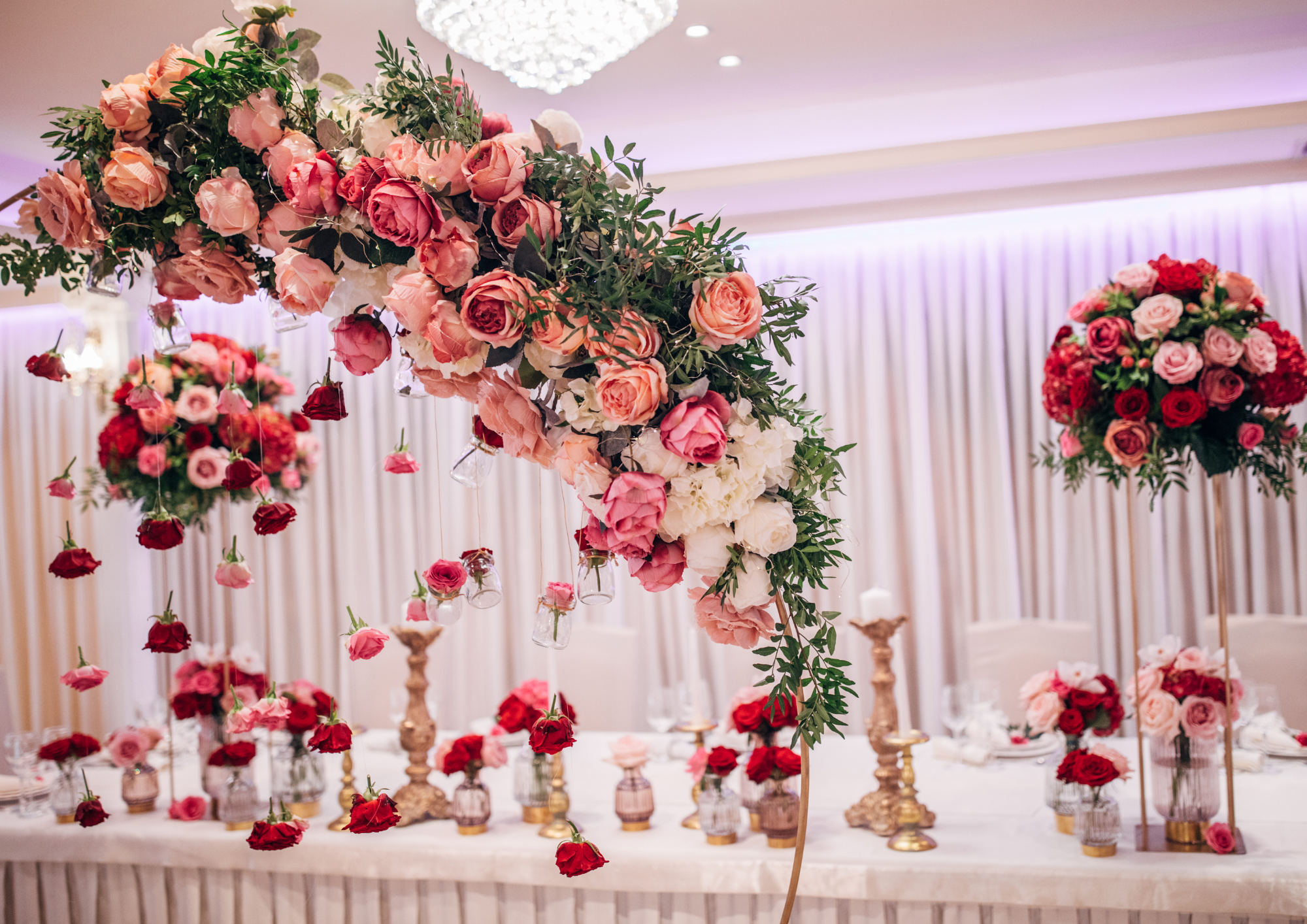 Großer Blumenbogen aus rosa Rosen in einem goldenen Bogen eingespannt